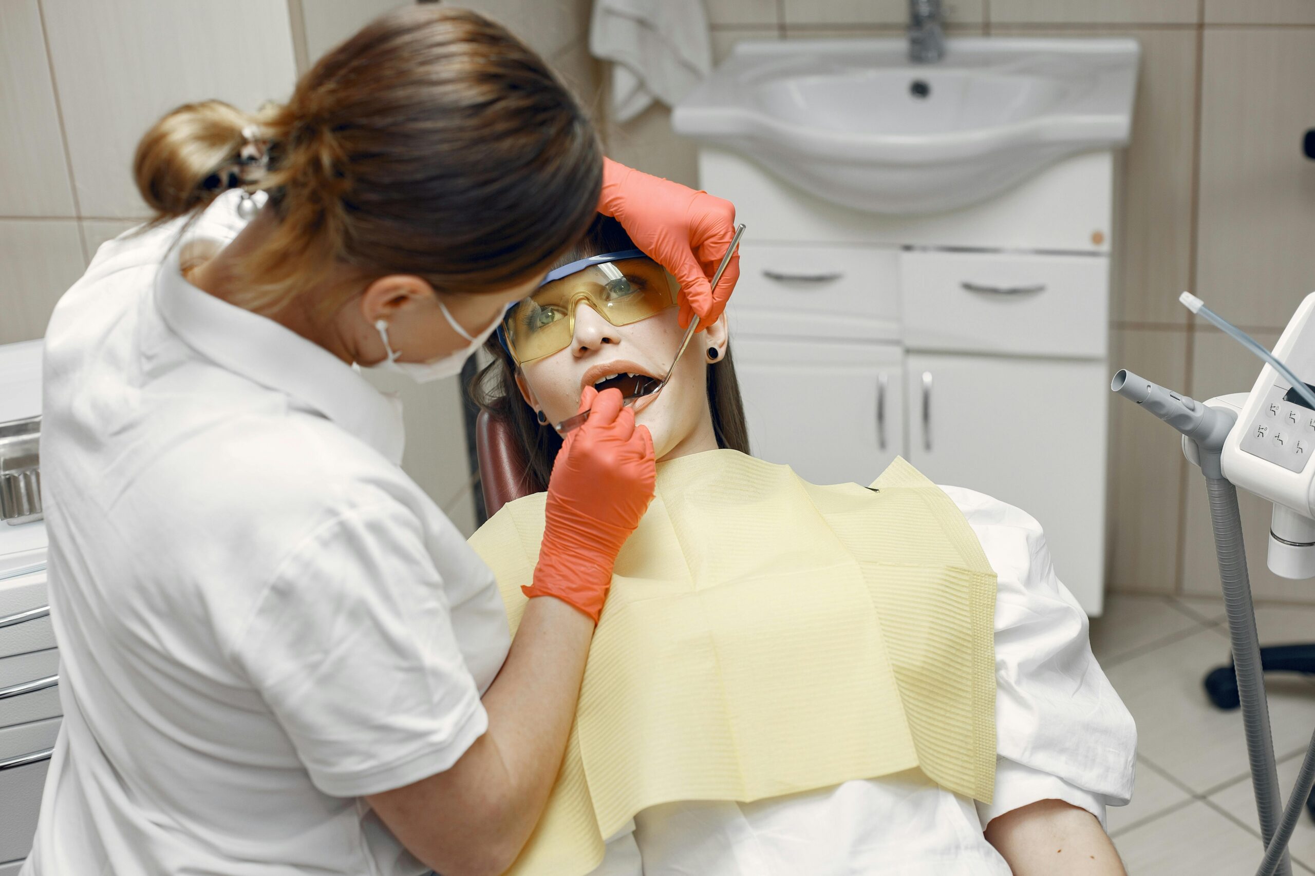 Professional dentist examines patient in a dental clinic with safety gear.
